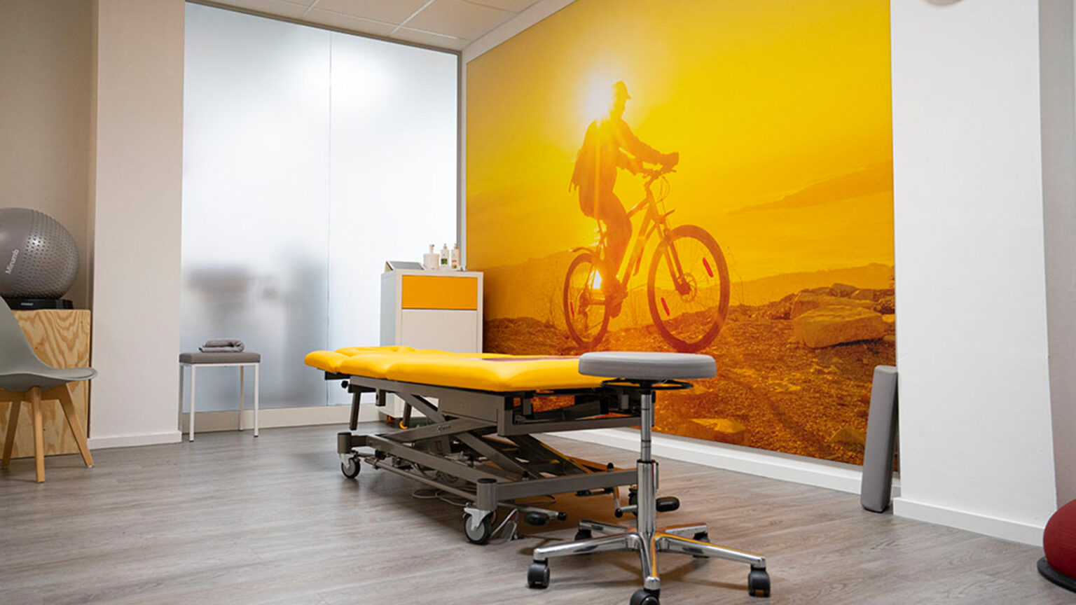 Moderner Massage- oder Physiotherapieraum mit entspannter Atmosphäre, einer Liege und passendem Zubehör.